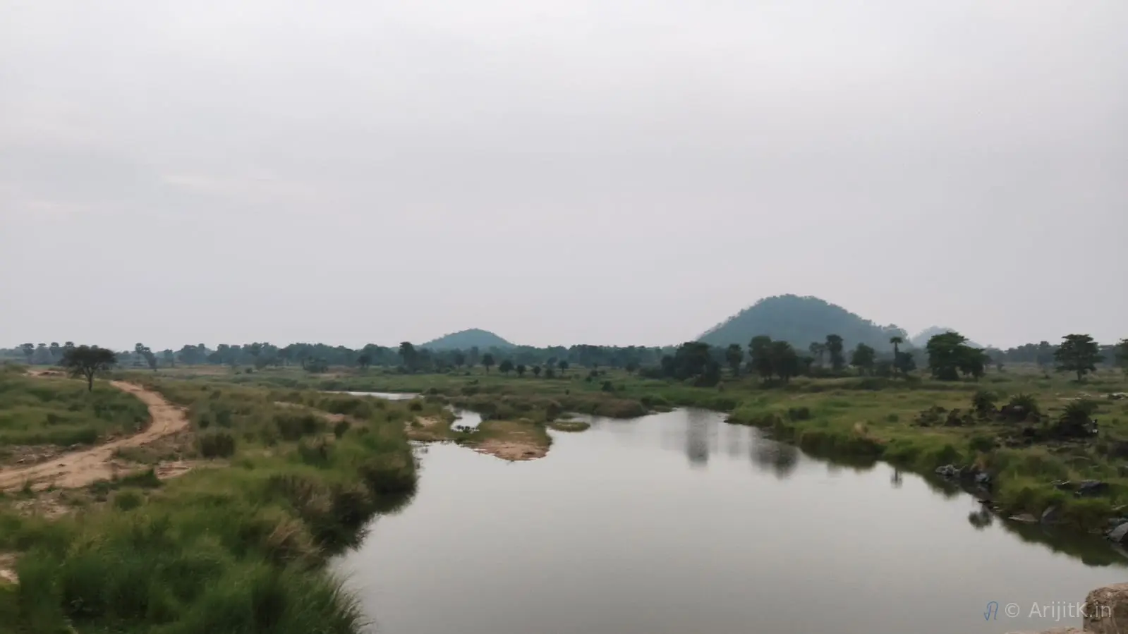 River flowing between dry hills under an overcast sky