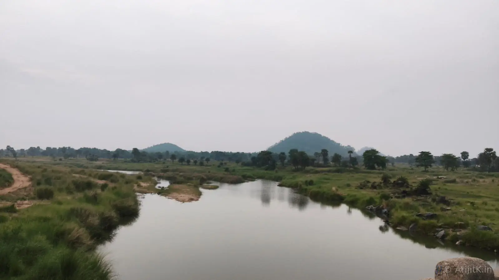 A winding river cutting through a dry valley at Paharpur